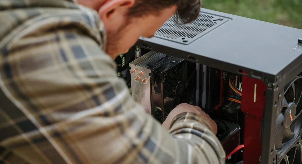 A person gently cleaning a computer fan with compressed air