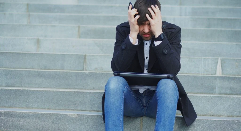 A person looking confused in front of a computer with a puzzled expression