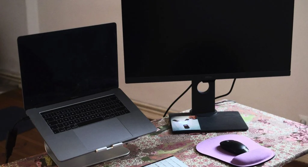 Photo of a laptop and desktop computer side by side in a workspace setup