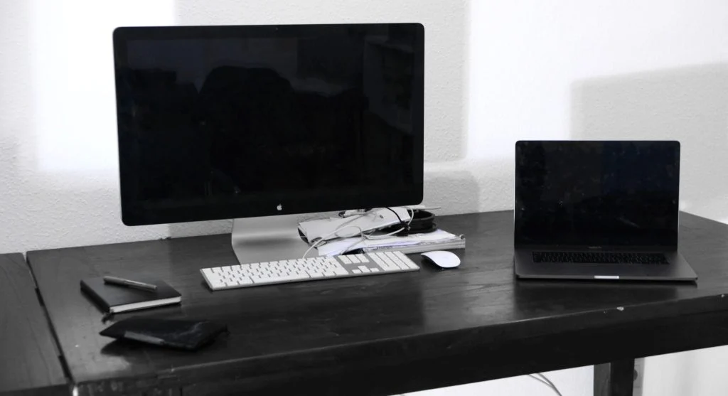 A laptop and desktop computer side by side, highlighting portability